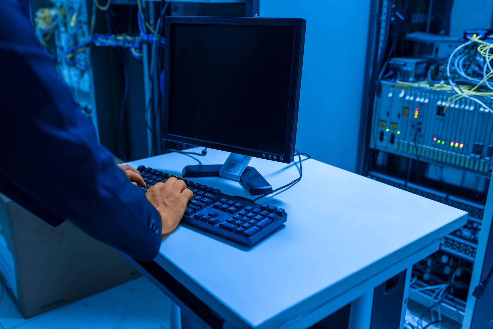 An IT engineer working at a workstation in a server room.